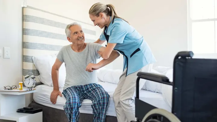 nurse helping elderly man out of bed